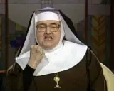 Zakonnica w okularach z zaciśniętą pięścią i otwartymi ustami.