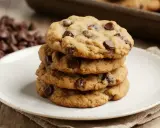 Pile de cookies aux pépites de chocolat, parfaits pour une recette de cookies moelleux. Des pépites de chocolat en arrière-plan.