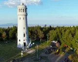 Wieża widokowa na szczycie góry, otoczona lasem. To popularne miejsce, gdzie zaczyna się wielka sowa trasa turystyczna.