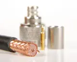 Przewód ekranowany z miedzianym oplotem, obok złoty pin i metalowe złącza.