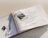 Otwarta księga gości z ozdobnym długopisem i napisem "love". Na otwartej stronie widnieją mądre życzenia ślubne od rodziców, ozdobione małym zdjęciem.