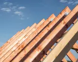 Drewniana konstrukcja dachu z belek pod błękitnym niebem.