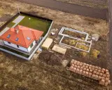 Działka rolno budowlana z gotowym domem i fundamentami pod kolejny. Materiały budowlane czekają na rozpoczęcie prac.
