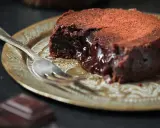 Fondant au chocolat cacao, cœur coulant, saupoudré de cacao, sur une assiette dorée avec une fourchette.