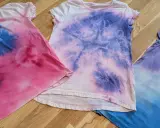 Batik mit Kindern: Drei bunte T-Shirts in Rosa, Lila und Blau, die nach einem kreativen Nachmittag aussehen.