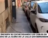Un coche eléctrico se carga en la calle, con cables cruzando la acera. Una forma poco convencional de como cargar coche electrico en la calle.