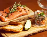 Świeży łosoś z rozmarynem i pieprzem, tartare w słoiczku, pieczywo i ogórek. Zdrowe łosoś kcal na drewnianej desce.