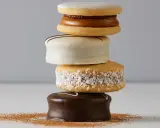 Una pila de alfajores, dulces típicos de Argentina y Uruguay, cubiertos de chocolate, coco y glaseado.