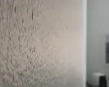 Närbild på en vägg där man har bredspacklat på tapet. Ytan är ojämn och texturerad.