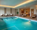 Elegancki basen hotelowy z turkusową wodą, wygodnymi leżakami i stylowymi meblami wypoczynkowymi.