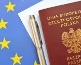 Polski paszport, długopis i flaga Unii Europejskiej.