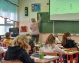 Nauczycielka dyplomowana pisze na tablicy, dzieci słuchają. Ciekawe, jakie nauczyciel dyplomowany zarobki ma w tej szkole.