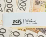 Logo ZUS na tle polskich banknotów 200 zł.