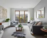 Elegante salón donde el gris y beige combinan a la perfección, con sofás cómodos, mesa de centro de madera y una original decoración de ramas en la pared.