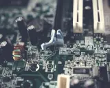 Fragment płyty głównej w formacie extended ATX z widocznymi kondensatorami, cewką i złączami.