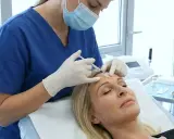 Medico esegue iniezione di botulino per chirurgia estetica sul viso di una donna.