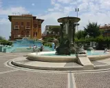 Fontana delle Sirene a Cattolica, con statue di sirene e tartarughe, circondata da edifici storici e una piazza acciottolata.