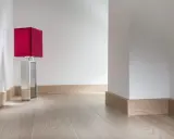 Enkel golvlistsinspiration i ljust trä som ramar in ett modernt rum med en röd bordslampa.