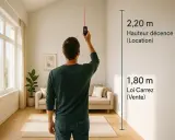 Un homme mesure la hauteur sous plafond d'un salon lumineux avec un appareil laser. Les mesures indiquent 2,20 m pour la décence locative et 1,80 m pour la loi Carrez.