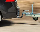 Czarne auto z zamontowanym hakiem holowniczym ciągnie przyczepę. Różne rodzaje haków holowniczych zapewniają bezpieczeństwo podczas transportu.