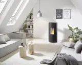 Poêle à granulés Rika en mode confort ou automatique, dans un salon moderne avec canapé gris, table basse en bois et lumière naturelle.