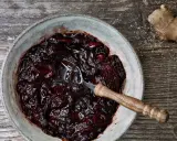 Dunkles, glänzendes Zwetschgen-Chutney in einer Schale, daneben ein Stück Ingwer und Zucker.