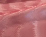 Tessuto rosa con pieghe che creano un affascinante effetto moiré, riflettendo la luce in modo cangiante.