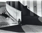 A silhouetted figure lies on a curved concrete ramp, arms outstretched, at the Janet Borden Gallery.