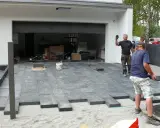 Pracownicy układają betonowe płyty, tworząc nowoczesny podjazd. Wygląda na to, że beton zamiast kostki to nowy trend.