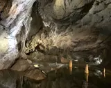 Wnętrze jaskini Bielskiej z wodą i stalagmitami.