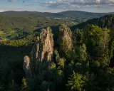 Skaliste szczyty, jak sokolik duży, górują nad lasem. Na jednym z nich platforma widokowa z turystą.