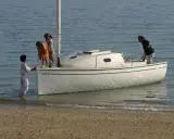 Une famille prépare son voilier, icône 6, pour une sortie en mer. Les enfants montent à bord, impatients de naviguer.