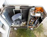Vista detallada de las partes de un aire acondicionado domestico: ventilador, compresores y serpentín.