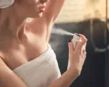 Kobieta aplikuje antyperspirant pod pachę, pokazując różnicę między dezodorantem a antyperspirantem.