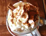 Un déliceux café liégeois recette : crème fouettée, cacao et bâton de cannelle dans un verre.