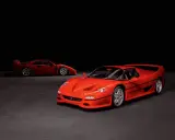 Zwei rote Ferraris, ein F50 und ein F40, stehen nebeneinander auf dunklem Grund.