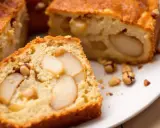 Tranche de gâteau poires amandes moelleux, parsemé de noisettes entières et de morceaux d'amandes.