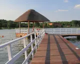 Drewniane molo nad zalewem Siemiatycze, z altaną krytą strzechą. W wodzie kąpie się osoba.