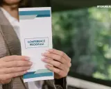 Oto jak wygląda ulotka z programem konferencji, trzymana w dłoniach.