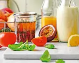 Ein Glas mit asiatischem Salatdressing, Tomaten, Passionsfrucht, Orange und Kräutern.