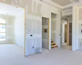 Wnętrze domu w budowie, ściany z płyt gipsowo-kartonowych, okno i schody.