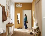 Ozdoby do przedpokoju: drewniane wieszaki, galeria obrazów, lustro, ławka i stylowa lampa tworzą przytulną przestrzeń.