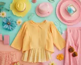 Un'esplosione di **colori caldi**: un outfit estivo con camicetta gialla, pantaloni rosa, cappelli e accessori floreali.