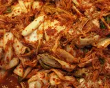 Zbliżenie na świeże, pikantne kimchi z kapusty pekińskiej, pokryte czerwoną pastą chili.