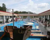 Ein Piratenschiff-Spielplatz in einem Freibad mit vielen Badegästen.