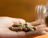 Kapsułki suplementów wysypują się z butelki na dłoń. To jeden ze sposobów, jak wzmocnić organizm.