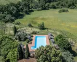 Piscina azzurra circondata da alberi e campi verdi, perfetta per una vacanza in Toscana.