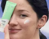 Une femme applique une crème hydratante sur sa joue. Une solution pour comment hydrater sa peau très sèche.