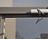 Türschließer nach DIN 18251, silberfarben, am oberen Rahmen einer Glastür montiert.