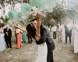 Novios besándose con humo verde, ¡ideas para una boda diferente! Invitados aplauden y celebran.